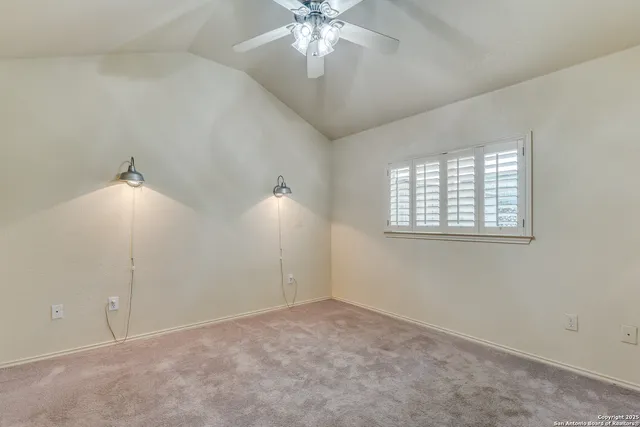 an empty room with chandelier fan and windows