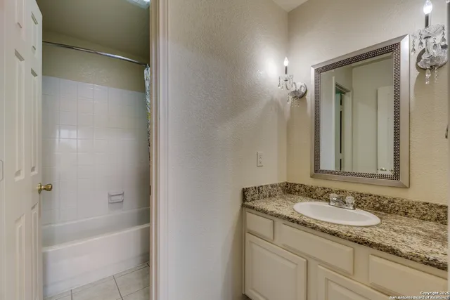 a bathroom with a granite countertop sink and mirror with bathtub