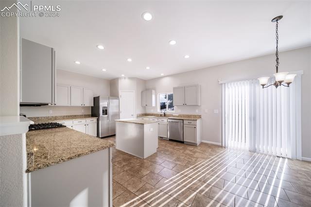 9356 Bethpage Road Peyton, CO 80831 - Photo 10 of 40 Kitchen with appliances with stainless steel finishes, a kitchen island, pendant lighting, and white cabinets