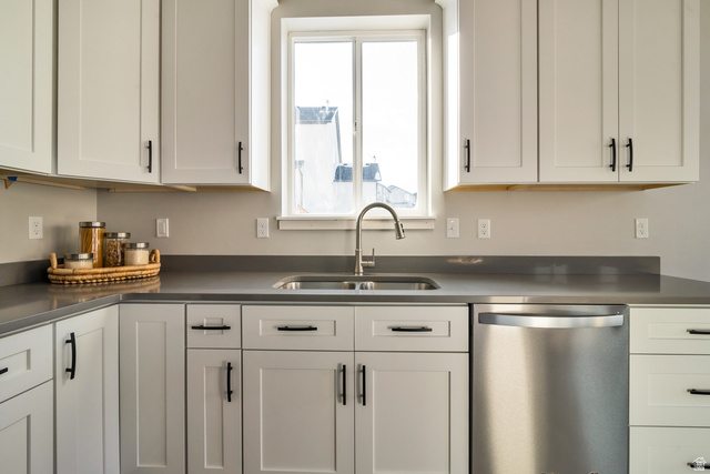 2449 Scarlet Road, Unit 249 Eagle Mountain, UT 84005 - Photo 13 of 26 Kitchen featuring white shaker-style cabinetry, dark countertops, a stainless steel sink with a gooseneck faucet, and a stainless steel dishwasher