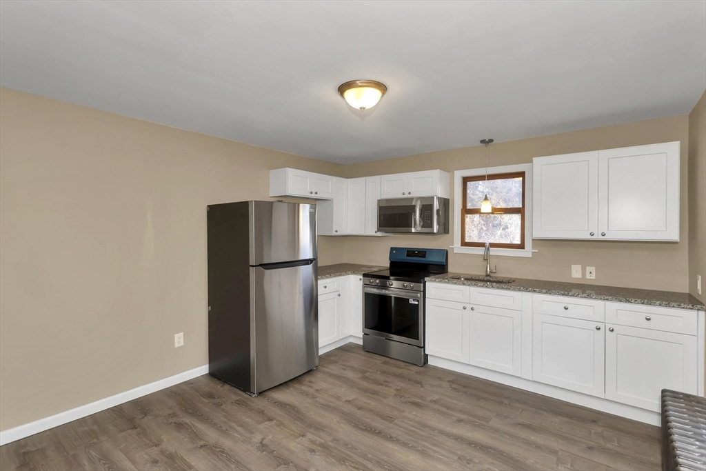 49 View Street Holyoke, MA 01040 - Photo 18 of 34 a kitchen with a refrigerator a stove top oven a sink and dishwasher with wooden floor