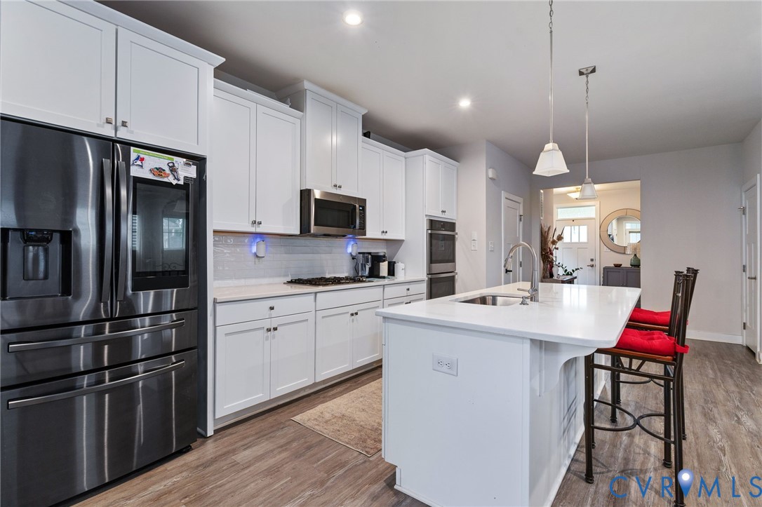 1605 German School Road Richmond, VA 23225 - Photo 8 of 27 a kitchen with stainless steel appliances kitchen island granite countertop a refrigerator a stove a sink dishwasher a dining table and chairs with wooden floor