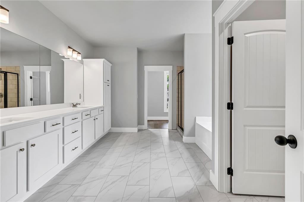 229 East Marable Street Monroe, GA 30655 - Photo 16 of 39 a spacious bathroom with a double vanity sink a mirror a bathtub and shower