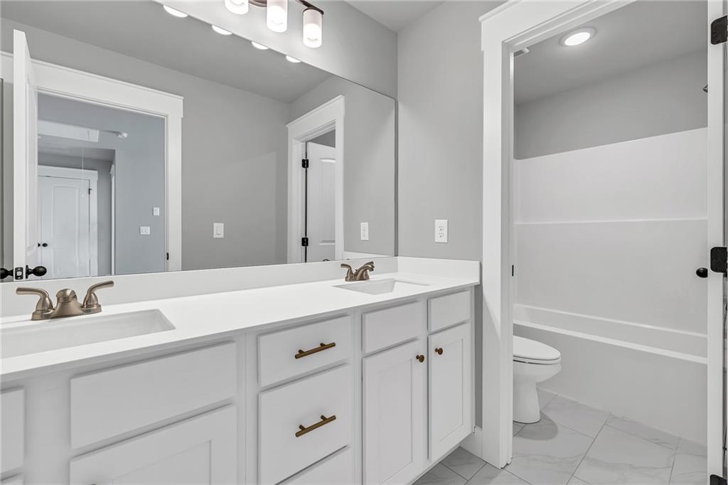 229 East Marable Street Monroe, GA 30655 - Photo 26 of 39 a bathroom with a granite countertop sink a toilet and a large mirror