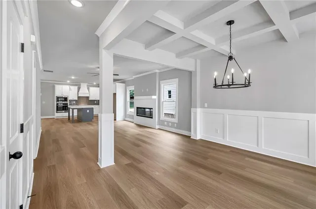 a view of a room with wooden floor kitchen view and a window