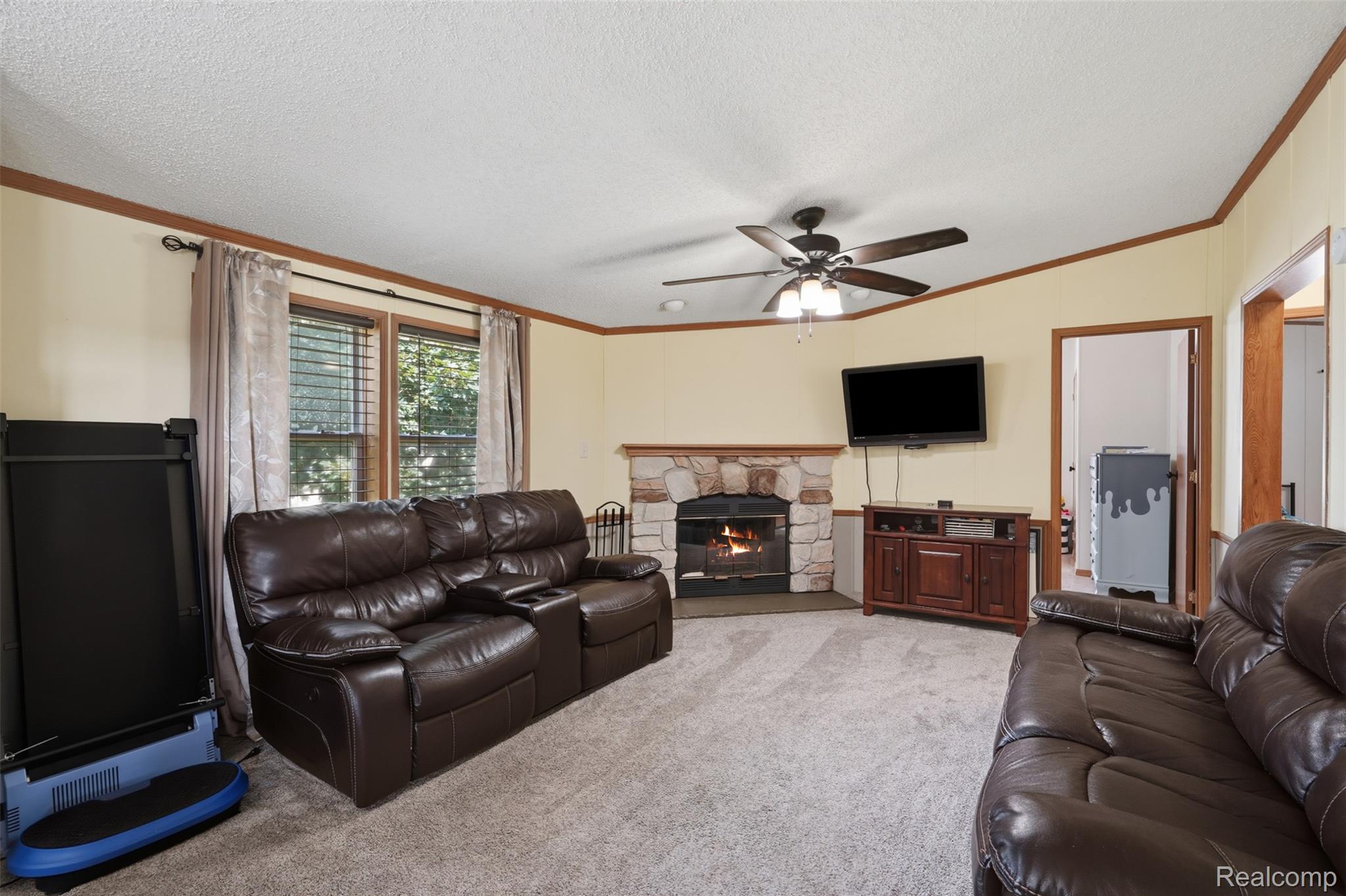 4634 Butternut Street Clarkston, MI 48348 - Photo 12 of 28 Spacious living area featuring a stone fireplace, carpet flooring, a ceiling fan, and natural light from a double window