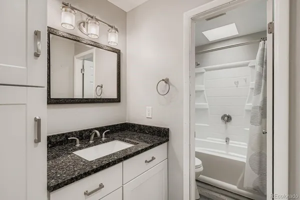 a bathroom with a granite countertop sink and a mirror