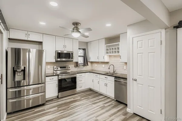 a kitchen with stainless steel appliances granite countertop a stove top oven a refrigerator a sink and dishwasher with wooden floor