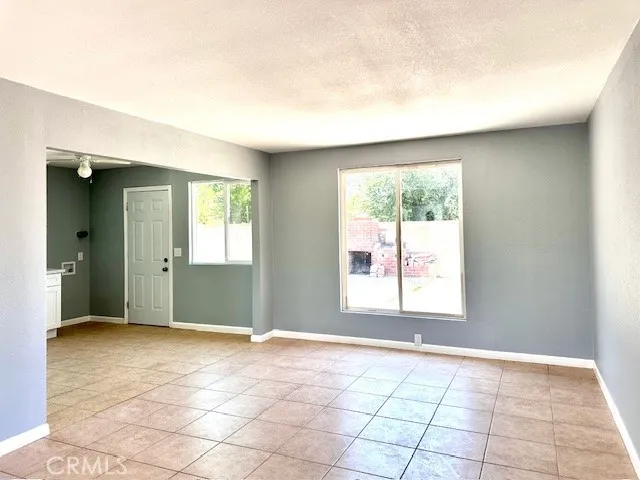 a view of an empty room with window and chandelier fan