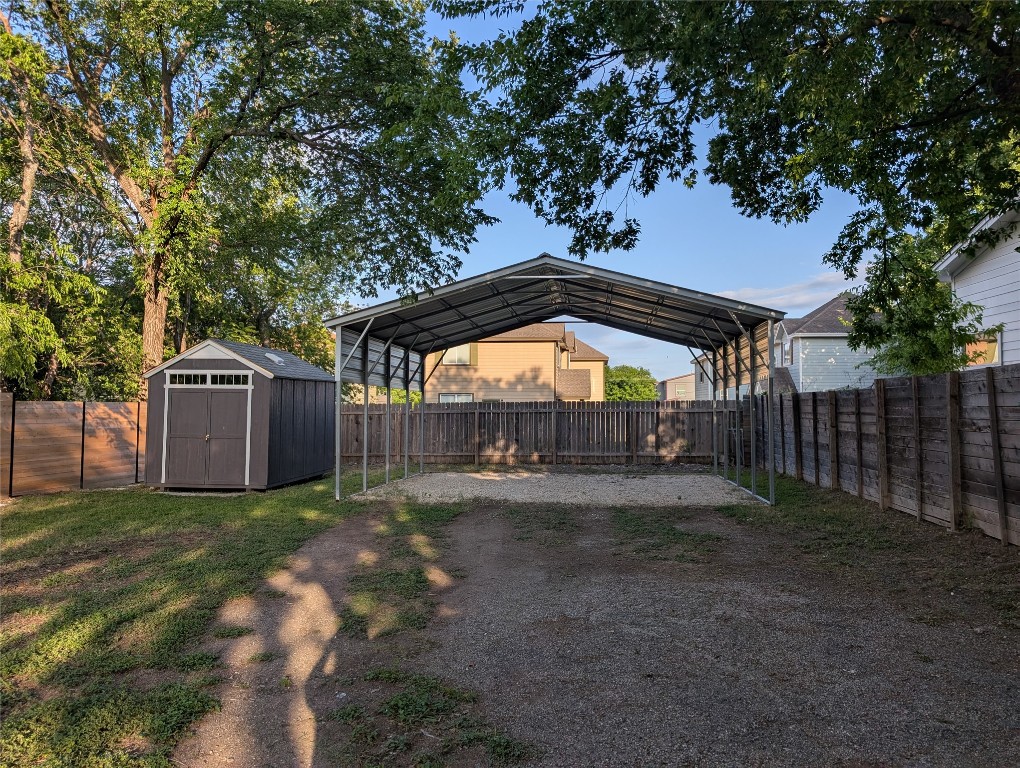 6915 Providence Avenue Austin, TX 78752 - Photo 19 of 27 Fenced backyard with dirt driveway, a storage unit, and a carport