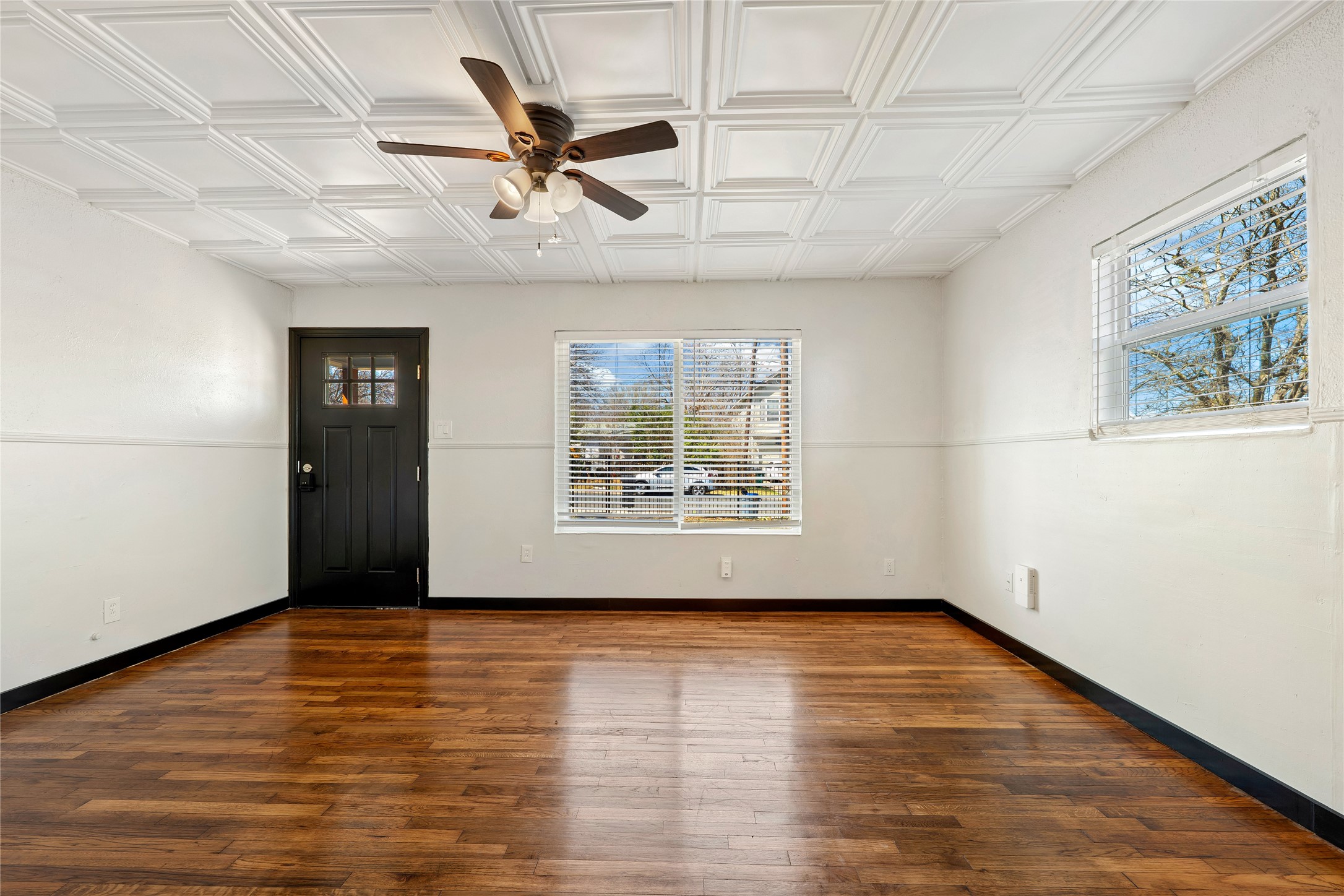 6915 Providence Avenue Austin, TX 78752 - Photo 6 of 27 an empty room with wooden floor chandelier fan and windows