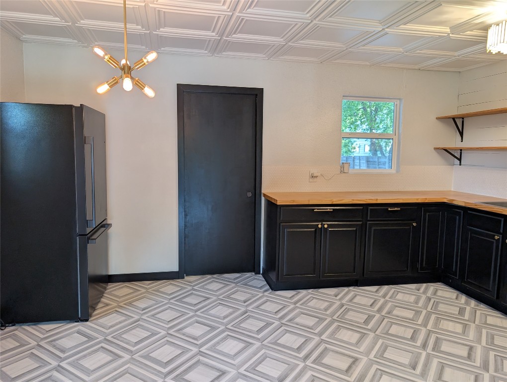 6915 Providence Avenue Austin, TX 78752 - Photo 7 of 27 Kitchen featuring dark cabinets, an ornate ceiling, open shelves, black appliances, and butcher block countertops