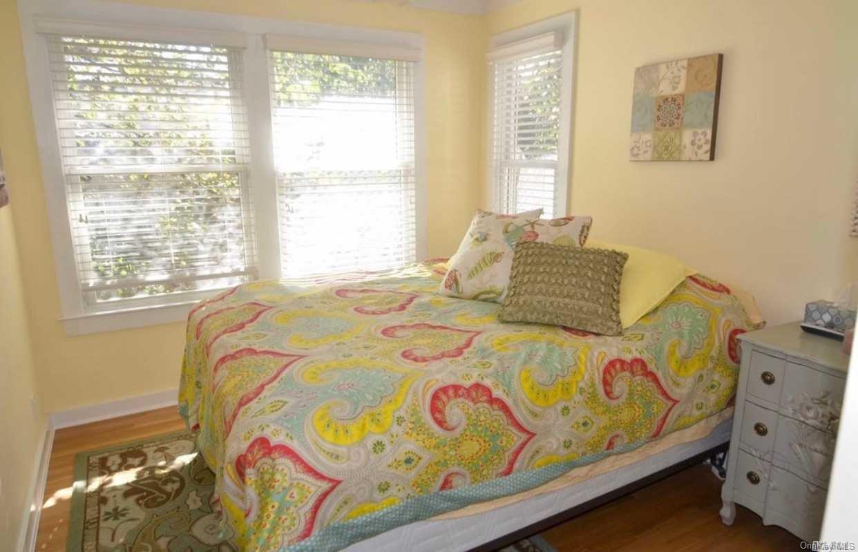 207 Wilmot Road Ocean Beach, NY 11770 - Photo 12 of 24 a bedroom with a bed that has a blanket on it and next to a window