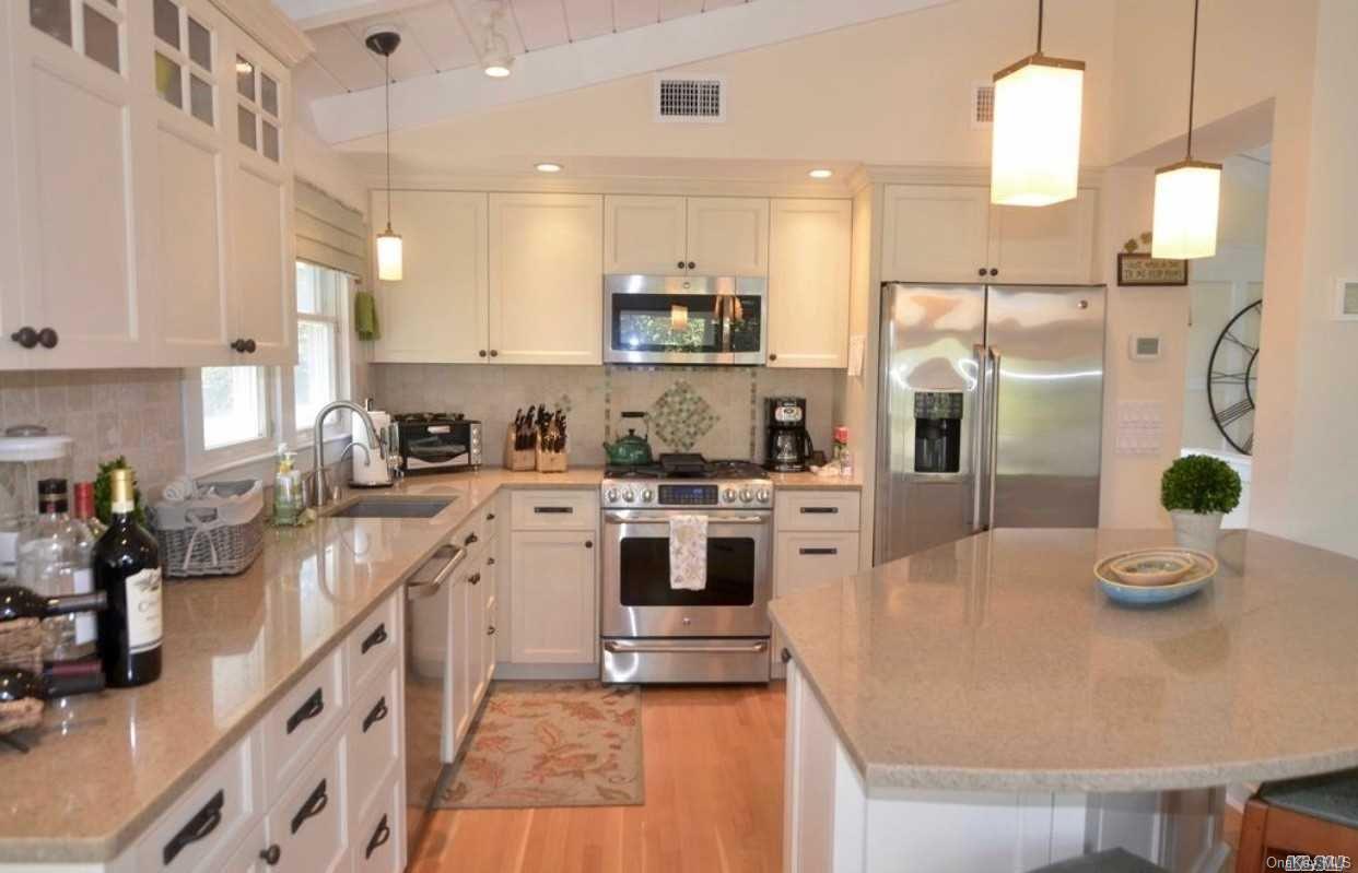 207 Wilmot Road Ocean Beach, NY 11770 - Photo 5 of 24 a kitchen with stainless steel appliances granite countertop a refrigerator a sink dishwasher a stove and white cabinets with wooden floor