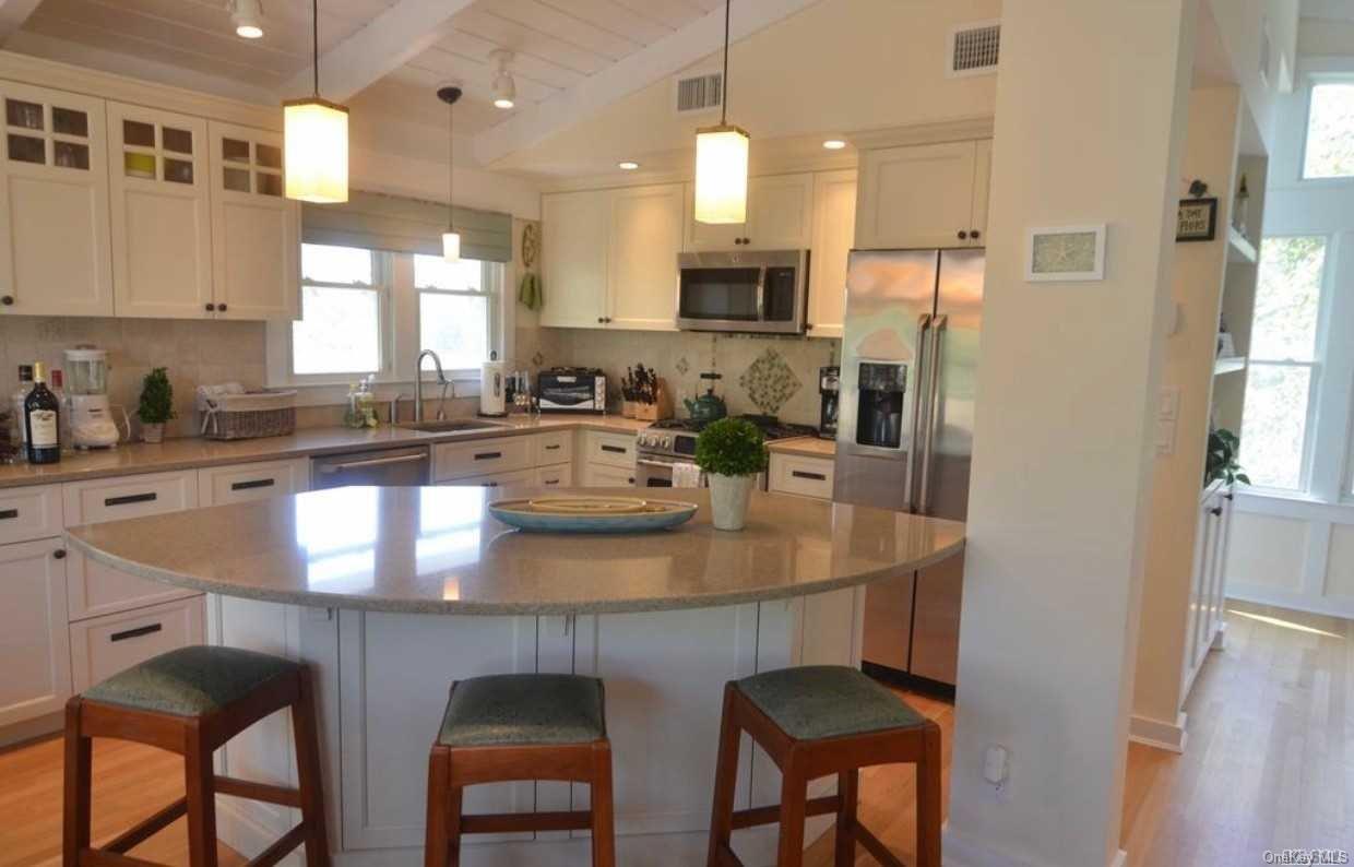 207 Wilmot Road Ocean Beach, NY 11770 - Photo 7 of 24 a kitchen with stainless steel appliances granite countertop a sink a stove a refrigerator dining table and chairs