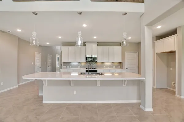 a large white kitchen with a stove a sink a refrigerator and a fireplace
