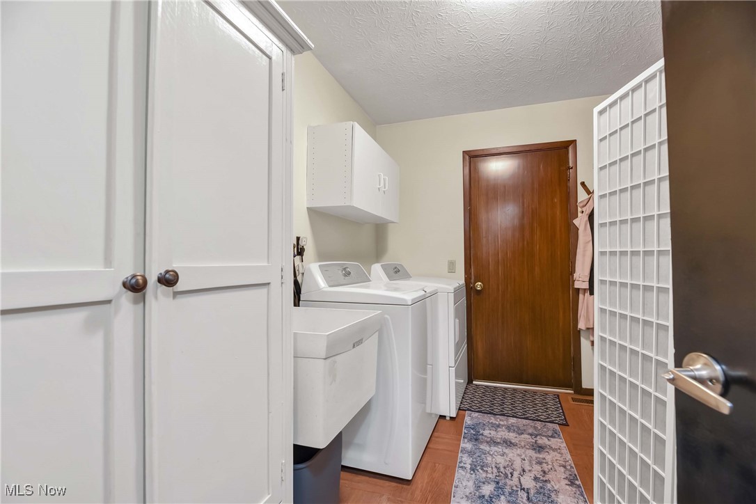 10778 Gate Post Road Strongsville, OH 44149 - Photo 21 of 40 Laundry area featuring sink, washer and clothes dryer, light wood-type flooring, a textured ceiling, and cabinets