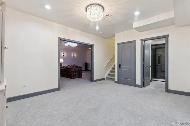 an empty room with chandelier fan and windows