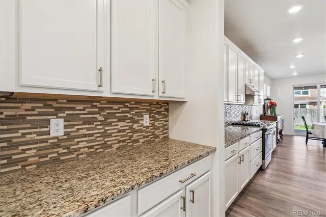 a kitchen with granite countertop white cabinets and stainless steel appliances