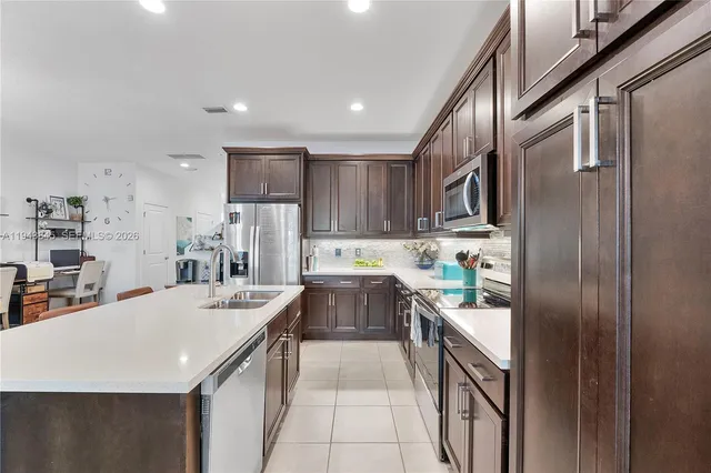 a large white kitchen with a stove a sink a dining table and chairs
