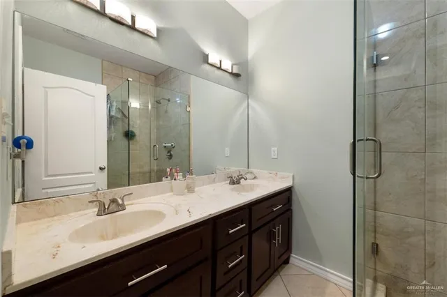 a bathroom with a double vanity sink a large mirror and a shower