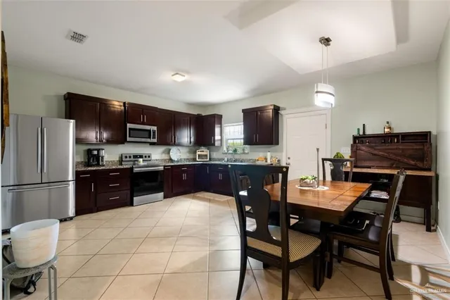 a kitchen with stainless steel appliances kitchen island granite countertop a stove a refrigerator a sink a dining table and chairs