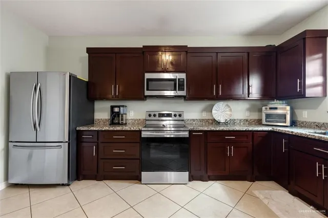 a kitchen with stainless steel appliances granite countertop wooden cabinets a refrigerator and a sink