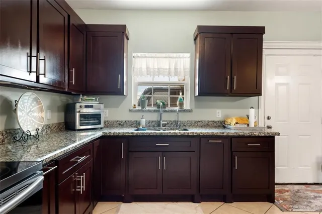 a kitchen with granite countertop stainless steel appliances a sink window and cabinets