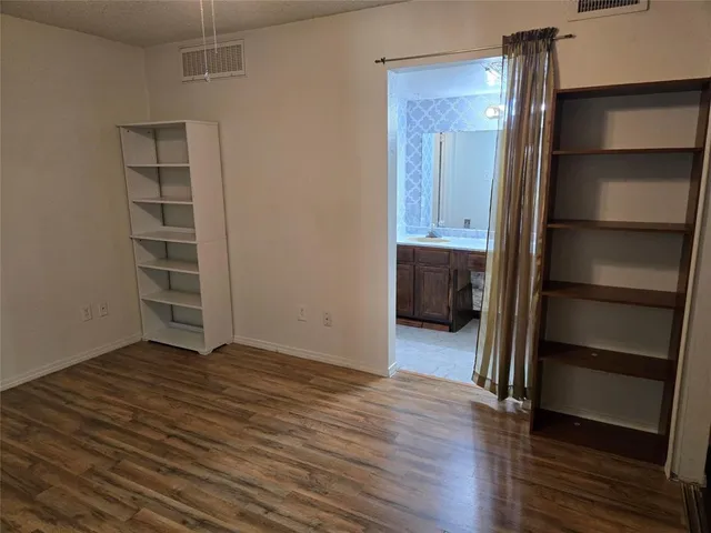 an empty room with wooden floor closet and windows