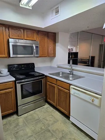 a view of a refrigerator in kitchen and an empty room with wooden floor