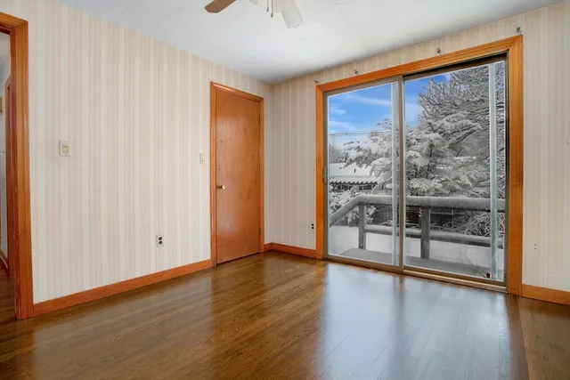 an empty room with wooden floor and windows with curtains