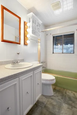 a bathroom with a granite countertop toilet sink and mirror