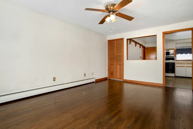 an empty room with wooden floor ceiling fan and windows