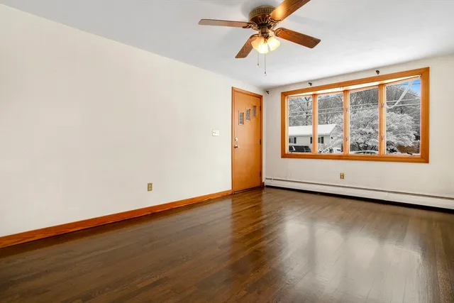 an empty room with wooden floor fan and windows