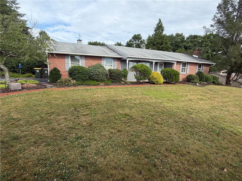 An inviting brick and siding ranch, featuring mature landscaping and a well-maintained lawn.