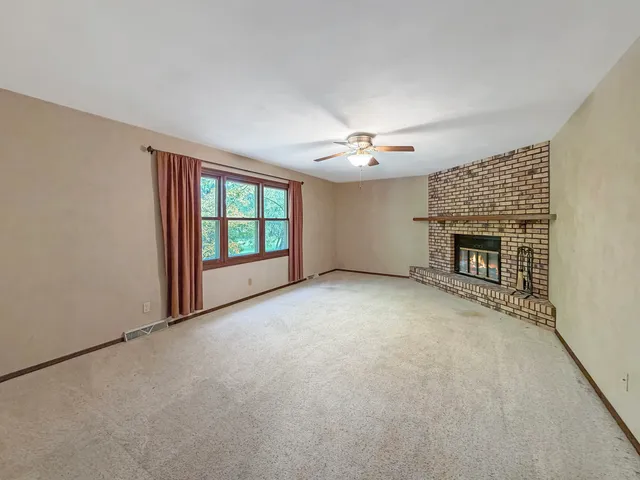 a view of an empty room with a fireplace and a window