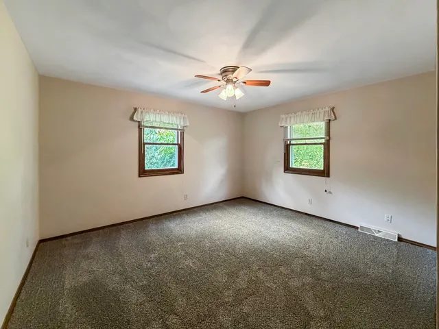 an empty room with windows and ceiling fan