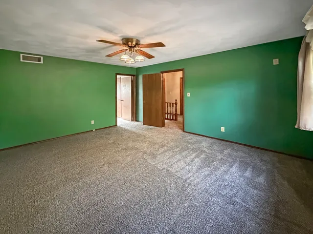 a view of an empty room with window and fan