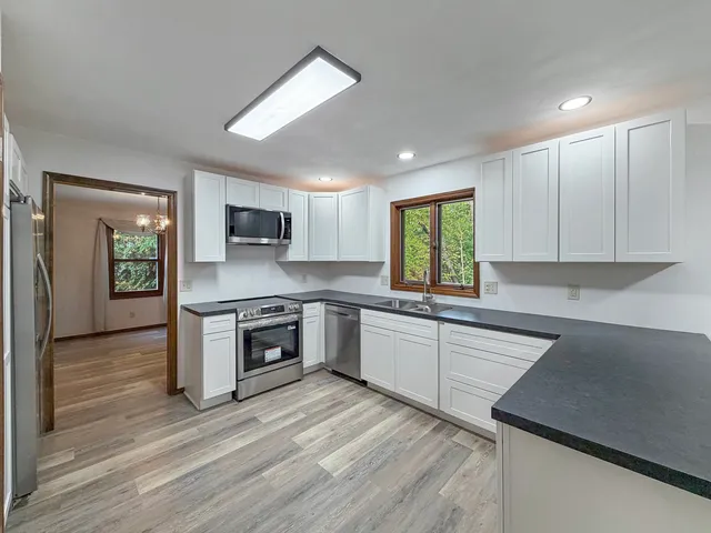 a kitchen with stainless steel appliances granite countertop wooden cabinets a stove a sink and a microwave