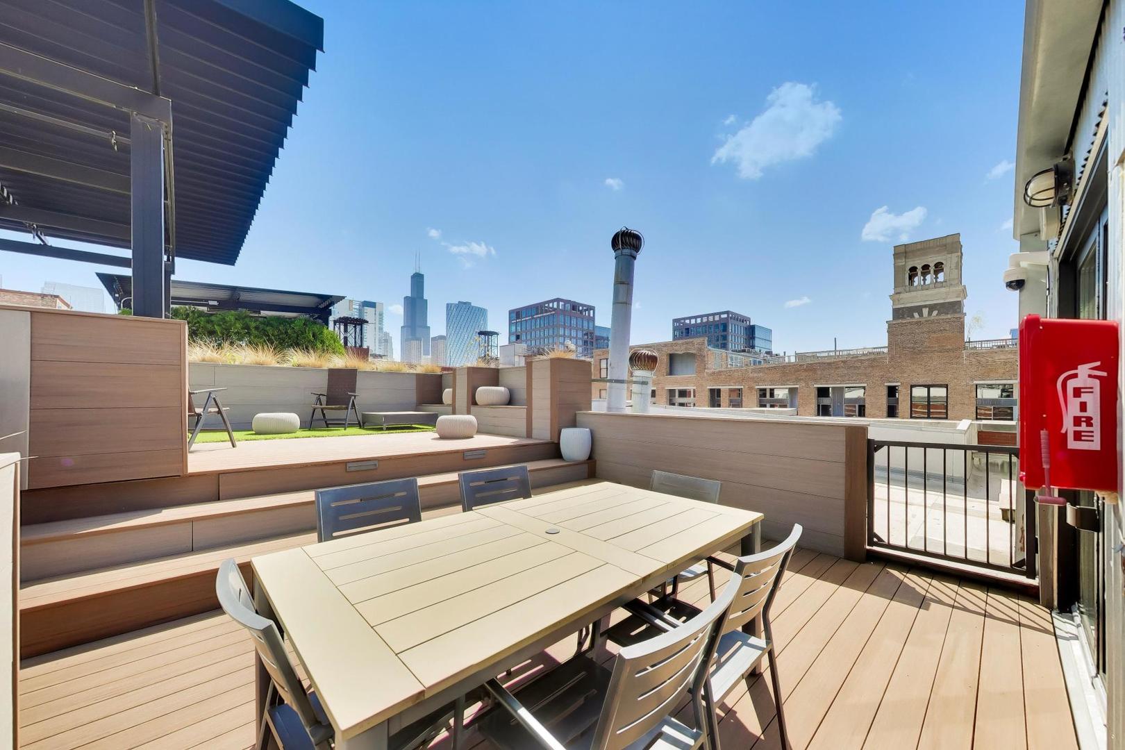 1000 West Washington Boulevard, Unit 145 Chicago, IL 60607 - Photo 42 of 45 a outdoor kitchen with stainless steel appliances kitchen island granite countertop a table chairs in it and wooden floors