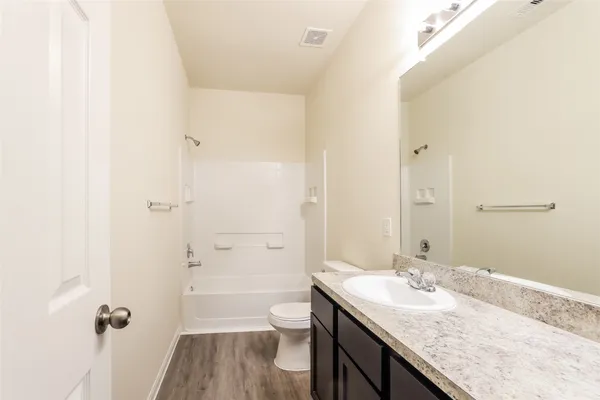 a bathroom with a granite countertop sink a toilet and shower