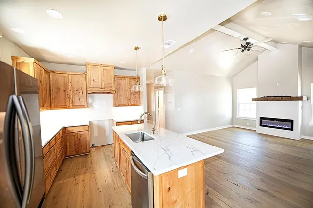 a kitchen with stainless steel appliances granite countertop a refrigerator a oven a sink and a dining table with wooden floor