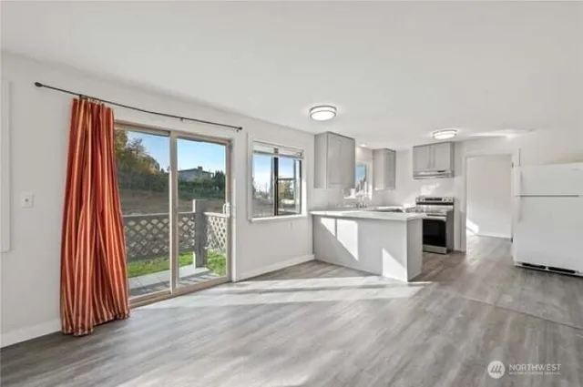 a large white kitchen with stainless steel appliances granite countertop a refrigerator oven a s sink and a large window