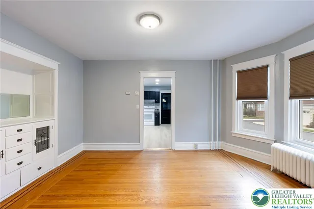 a view of an empty room with window and wooden floor