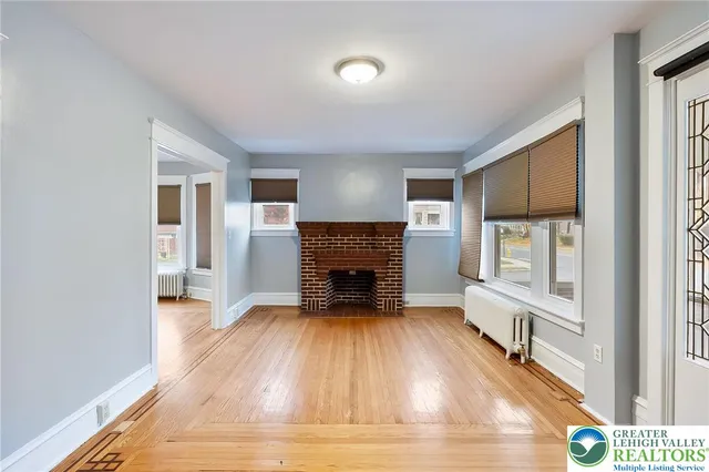 a view of a livingroom with a fireplace a ceiling fan and wooden floor