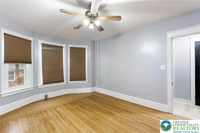 a view of an empty room with a window and ceiling fan