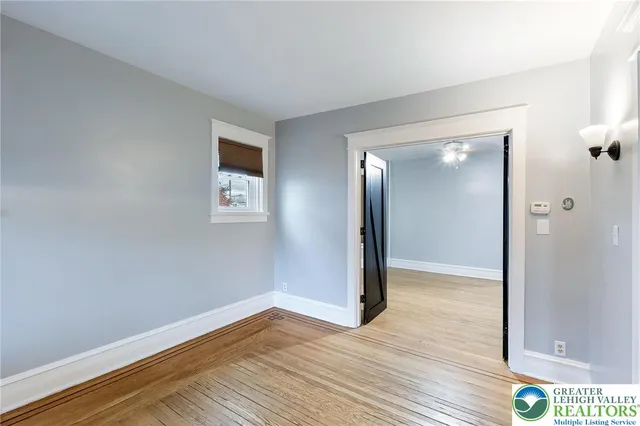 a view of an empty room with wooden floor and a window