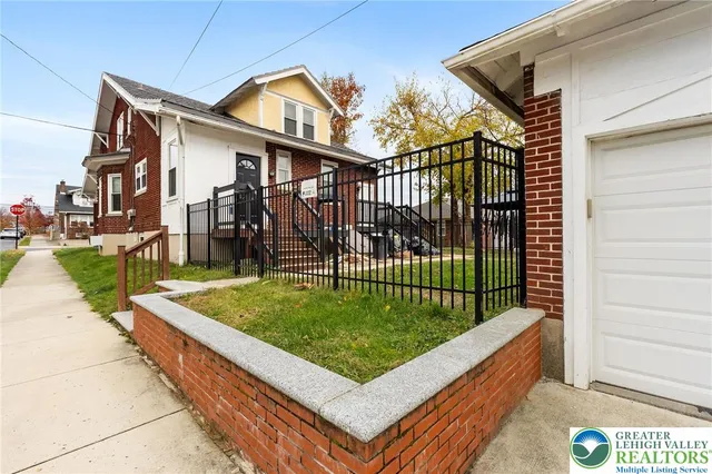a view of a white house with a small yard and plants
