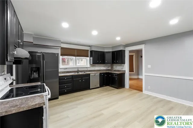 a kitchen with stainless steel appliances kitchen island granite countertop a refrigerator a sink a stove a oven a dining table and chairs