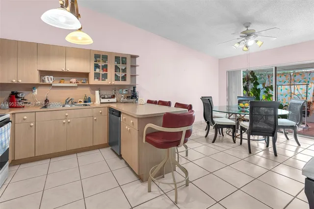 a kitchen that has a sink a stove a dining table and chairs with white cabinets